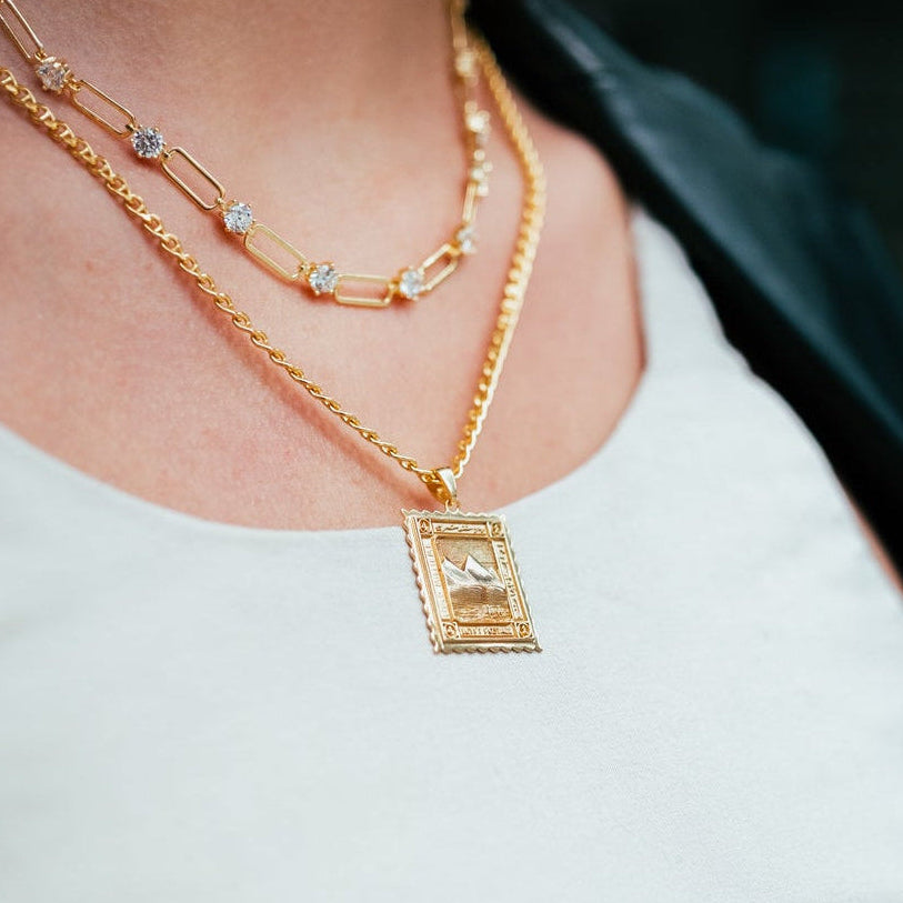 Close-up of a person wearing a gold necklace with a pendant.